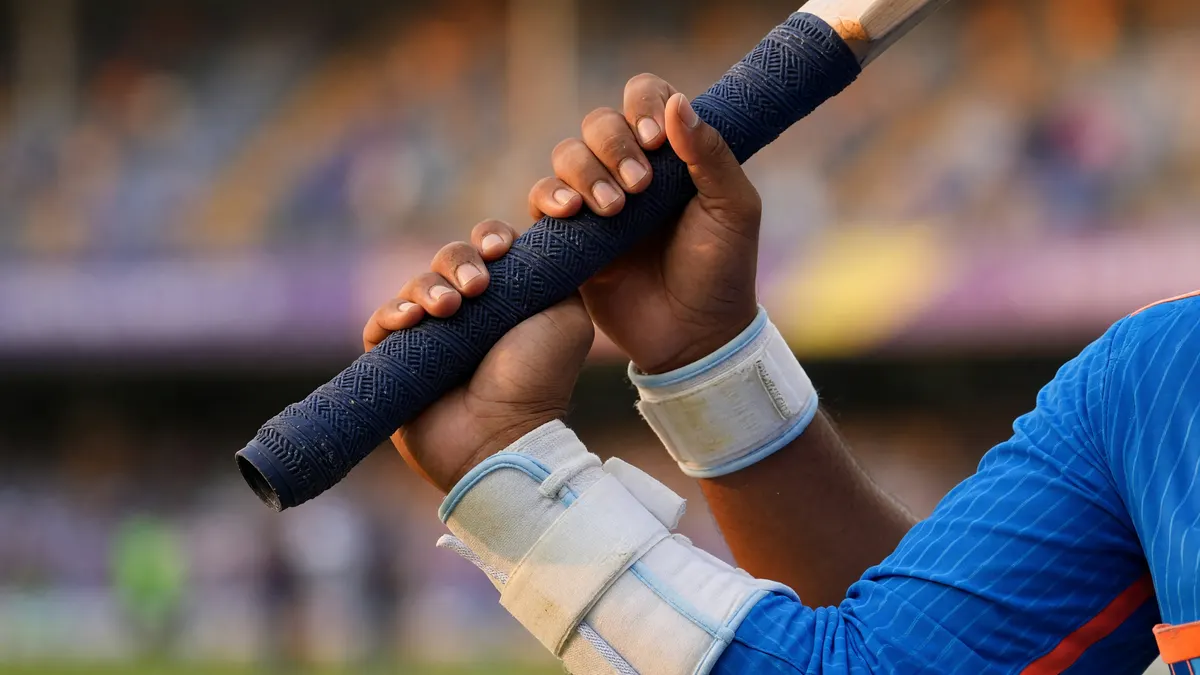 Editorial cricket photography close-up of a batsman wrist guard and grip on the bat handle